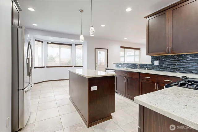 a kitchen with stainless steel appliances granite countertop a stove top oven a sink and dishwasher a refrigerator with wooden cabinets