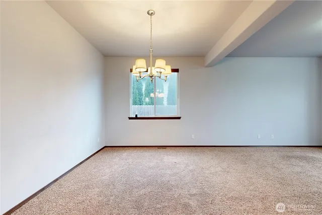 an empty room with a window and chandelier