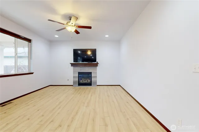 a view of an empty room with wooden floor and a fireplace