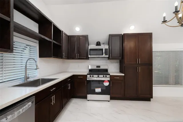 a kitchen with stainless steel appliances granite countertop a refrigerator a sink and wooden cabinets