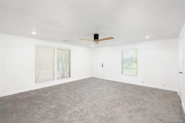an empty room with a window and ceiling fan