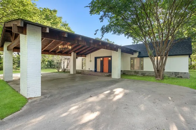 a view of a house with a yard and large tree