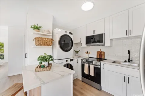 a kitchen with stainless steel appliances granite countertop a sink a stove top oven a chimney and a potted plant