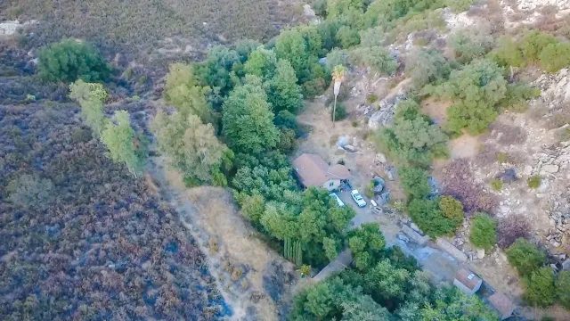 an aerial view of mountain with yard and tree in the background