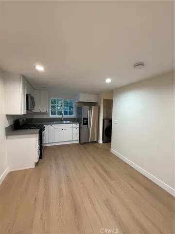 a kitchen with a refrigerator a sink and wooden floor