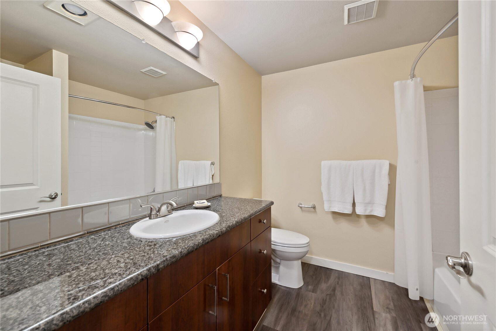 108 5th Avenue South, Unit 506 Seattle, WA 98104 - Photo 15 of 17 a bathroom with a granite countertop sink toilet a mirror and shower