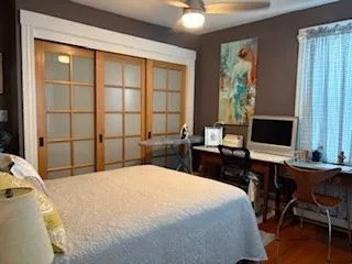 a bedroom with a large bed and a computer on the desk next to a window