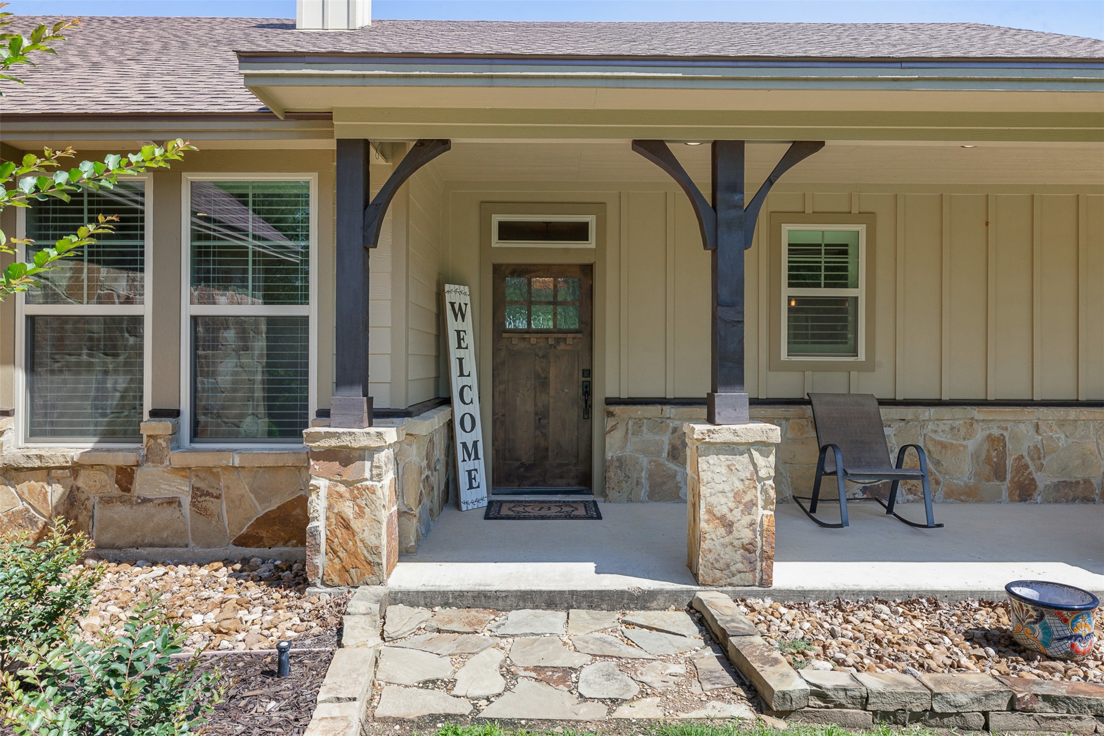 1306 22 Hills Road Gause, TX 77857 - Photo 2 of 40 Covered front porch featuring flagstone accents, robust columns with decorative corbels, a wood-finish entry door with glass inserts, and board-and-batten siding