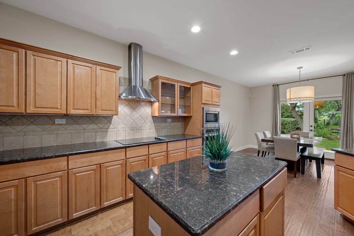 5715 Misty Hill Cove Austin, TX 78759 - Photo 11 of 40 a kitchen with stainless steel appliances granite countertop sink stove dining table and chairs