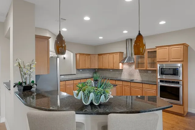 a kitchen with stainless steel appliances granite countertop a sink a stove and a wooden floors