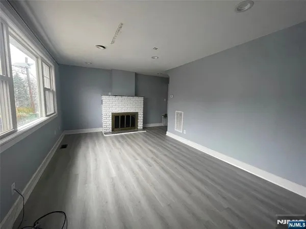 an empty room with windows fireplace and wooden floor