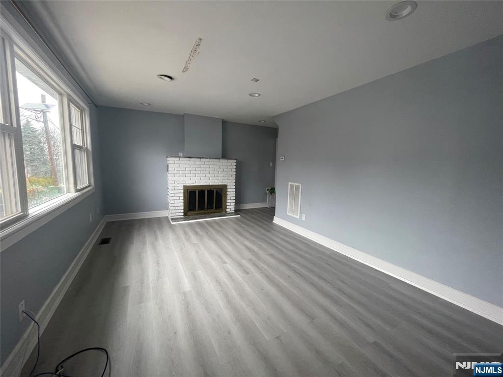 35 Chestnut Street, Unit 1F Wallington, NJ 07057 - Photo 2 of 9 an empty room with windows fireplace and wooden floor