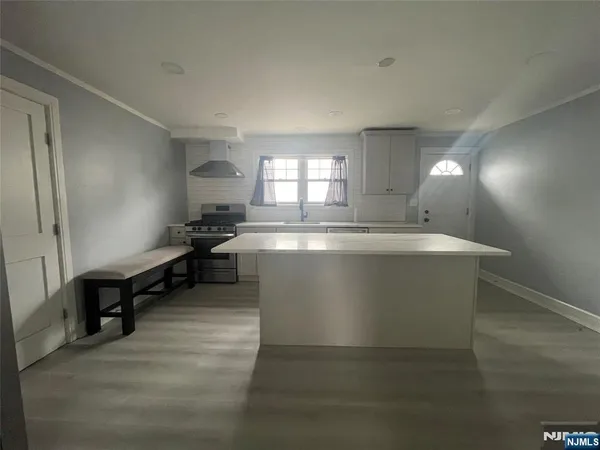 a large white kitchen with kitchen island granite countertop a sink a stove and a refrigerator