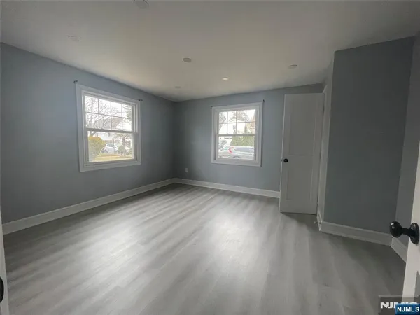 a view of an empty room with wooden floor and windows