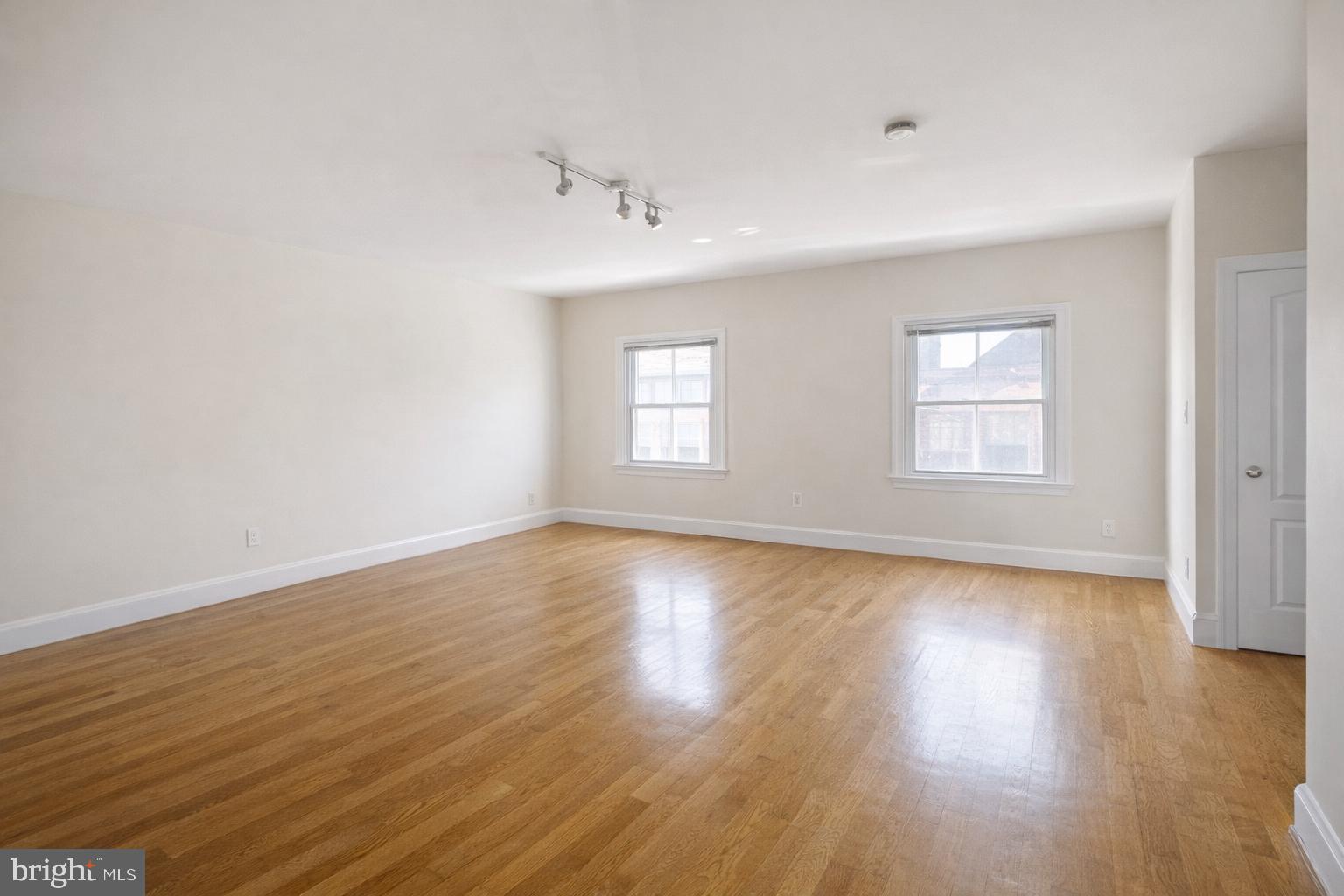 1701-03 Spruce Street, Unit 4F Philadelphia, PA 19103 - Photo 2 of 7 an empty room with wooden floor and windows