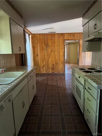 a kitchen with granite countertop a sink a stove oven and cabinets