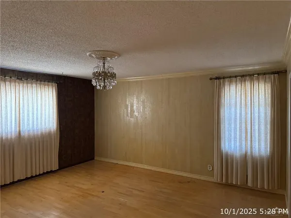 an empty room with chandelier fan and windows
