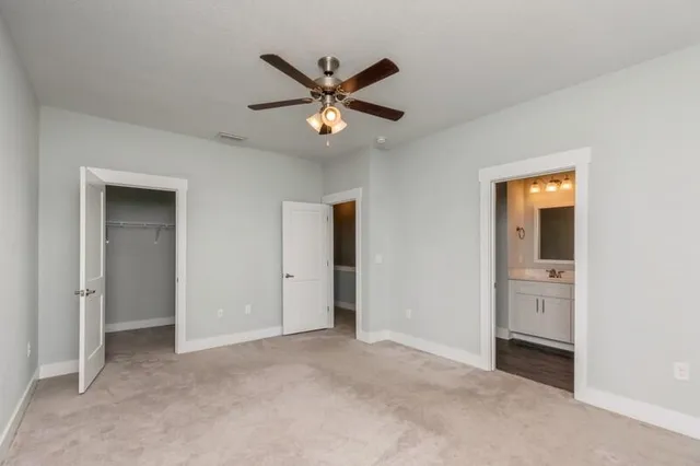 a view of an empty room with closet and a ceiling fan