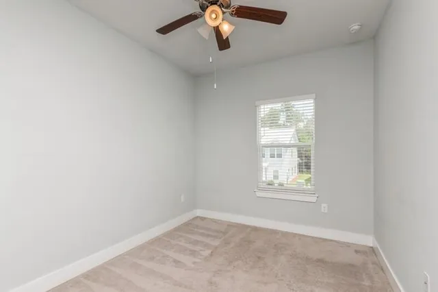an empty room with windows and chandelier fan