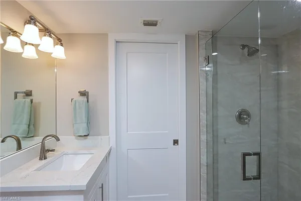 a bathroom with a sink a mirror a vanity and shower