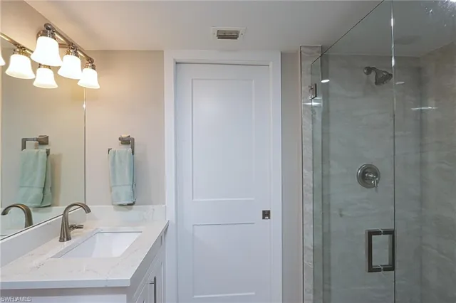 a bathroom with a sink a mirror a vanity and shower