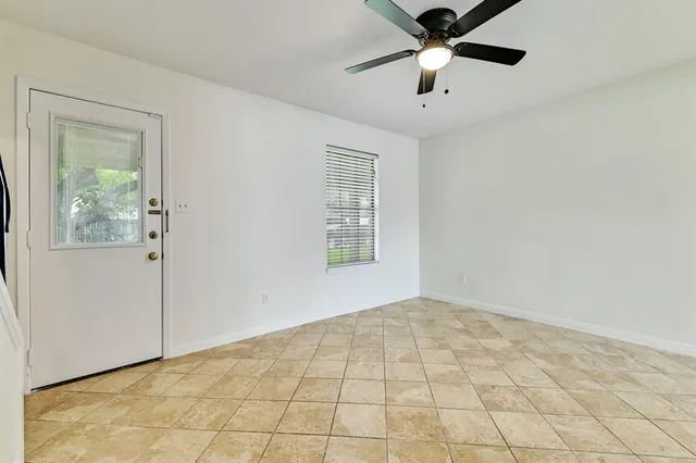 a view of an empty room with window and chandelier fan