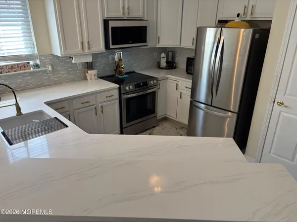 a kitchen with stainless steel appliances granite countertop a stove a refrigerator and a microwave