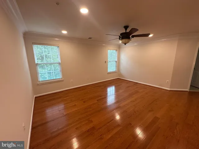 a view of empty room with wooden floor and fan