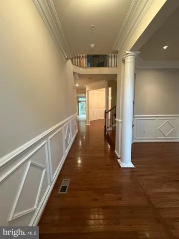 a view of an empty room with wooden floor and stairs