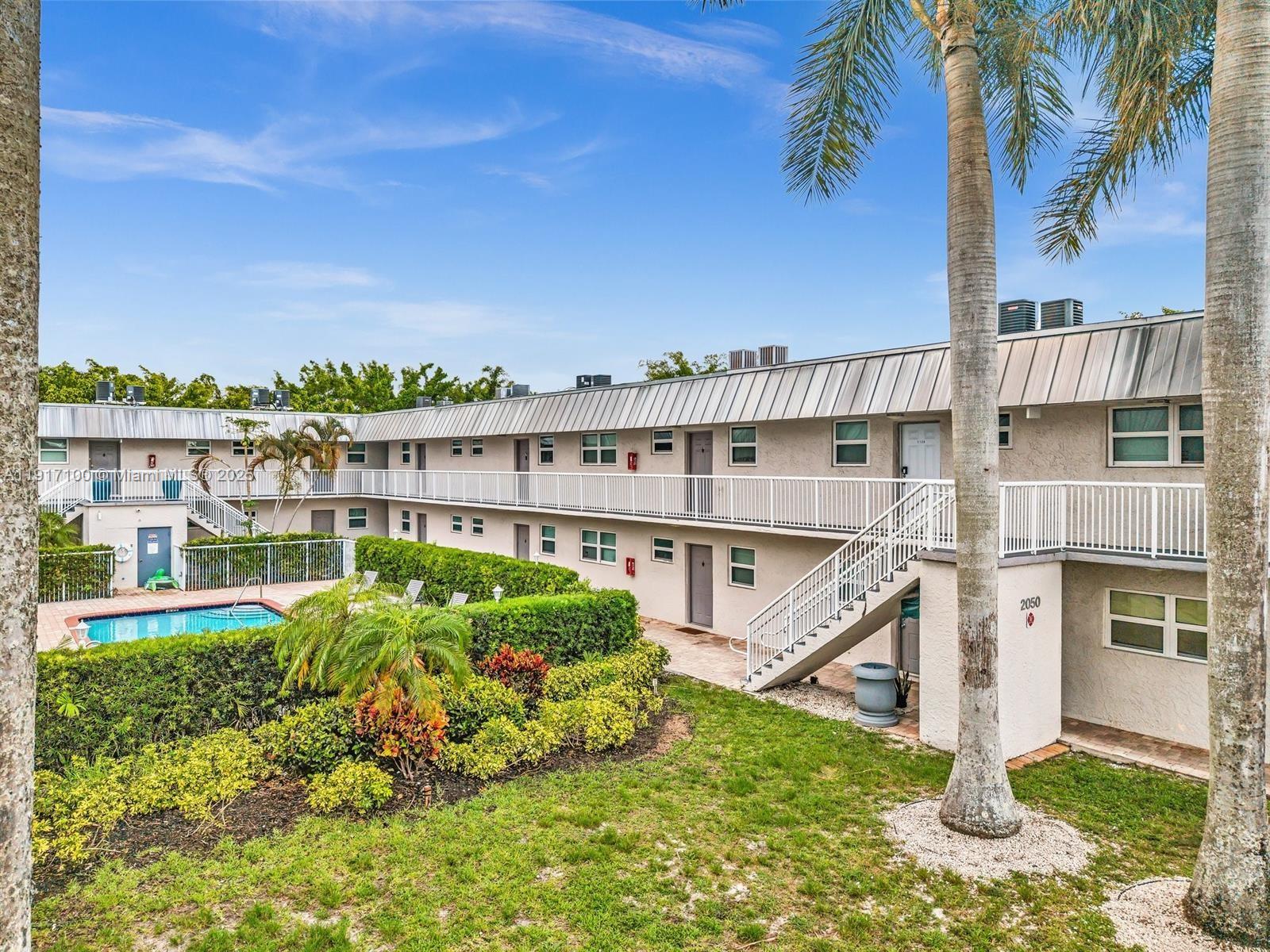 2050 Northwest 89th Avenue, Unit 211 Pembroke Pines, FL 33024 - Photo 2 of 14 a view of a house with a yard and potted plants