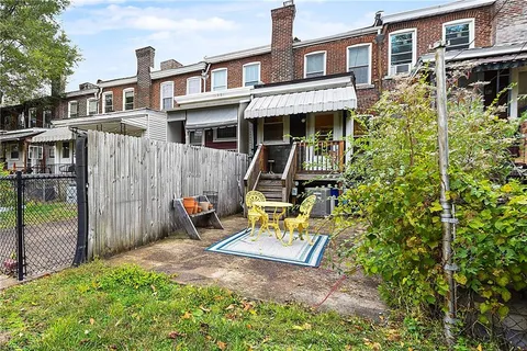 a view of a brick house with large windows and wooden fence