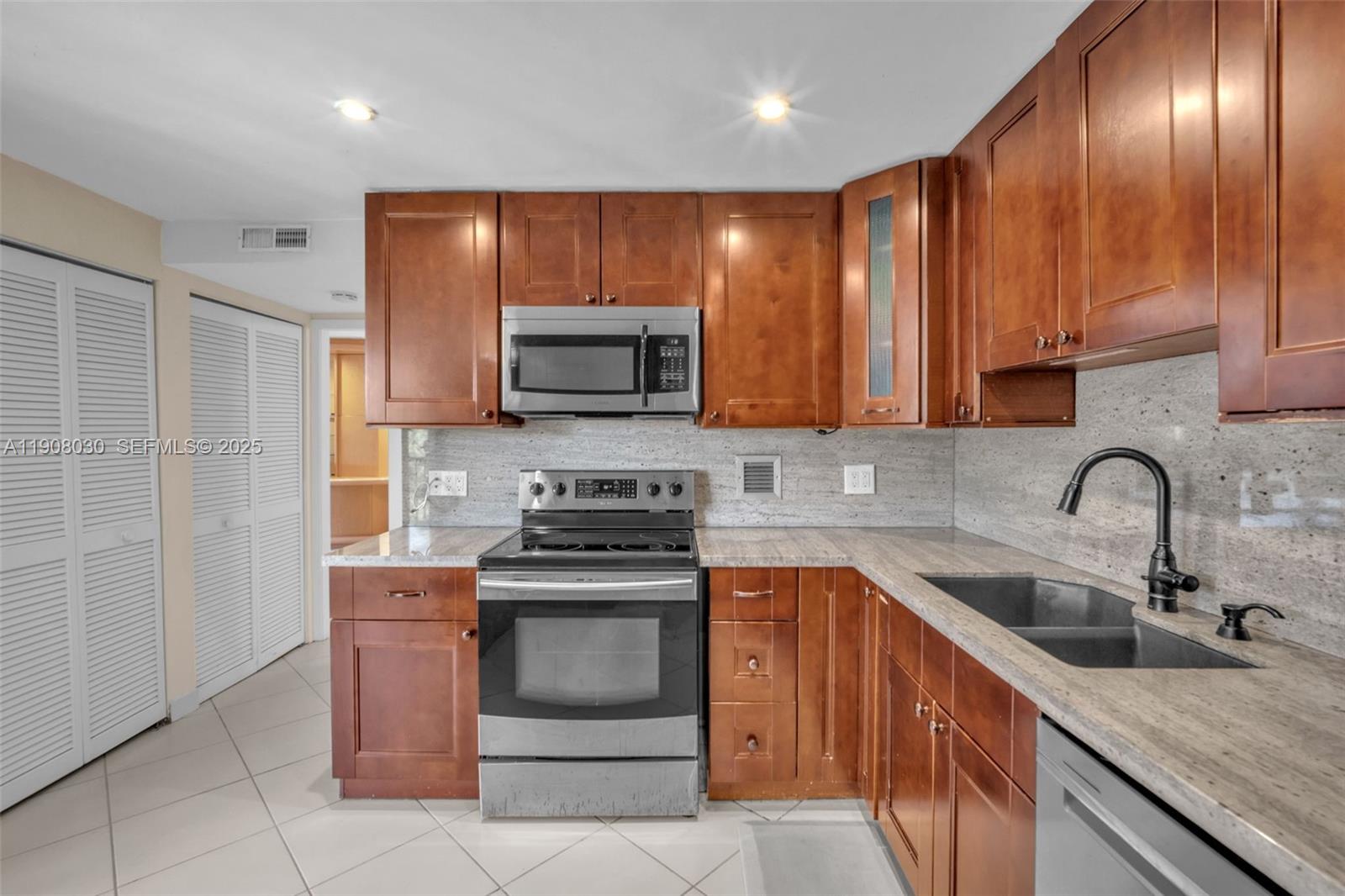 2810 North 46th Avenue, Unit F655 Hollywood, FL 33021 - Photo 28 of 52 a kitchen with stainless steel appliances wooden cabinets a sink and a stove