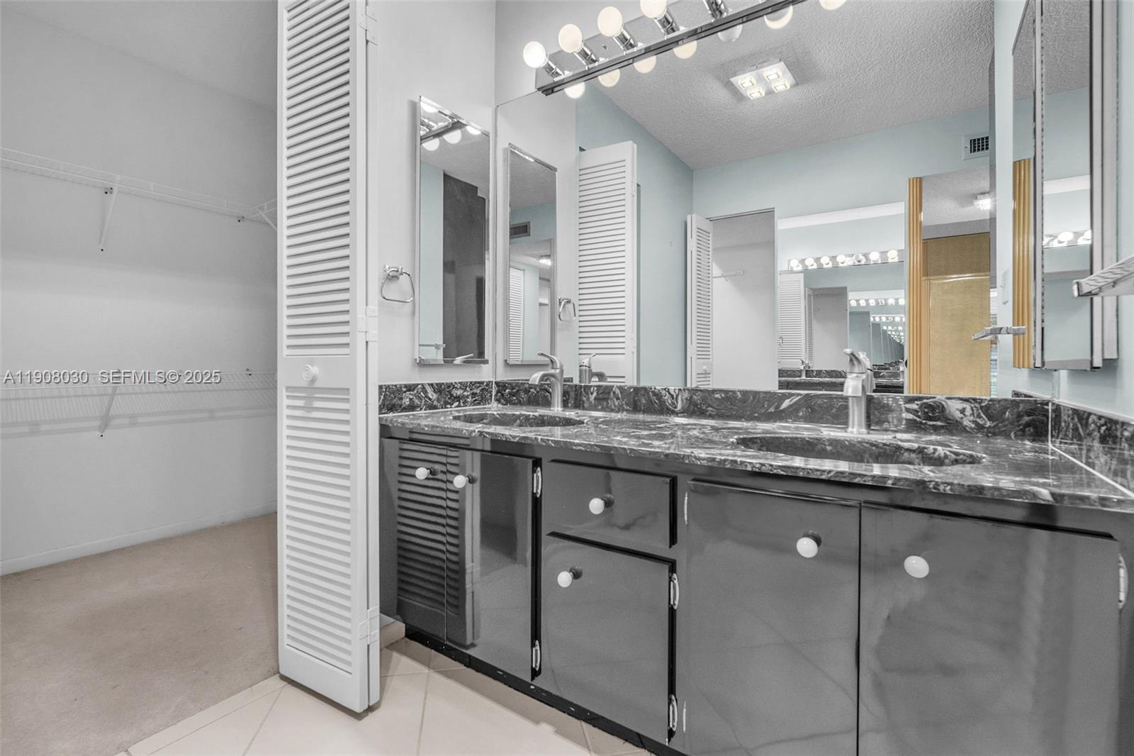 2810 North 46th Avenue, Unit F655 Hollywood, FL 33021 - Photo 40 of 52 a bathroom with a granite countertop sink a large mirror and a shower