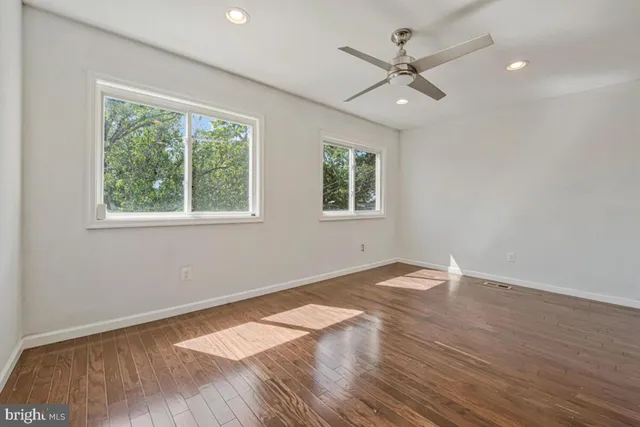 an empty room with wooden floor and windows