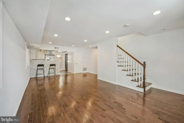 a view of an empty room with wooden floor and stairs
