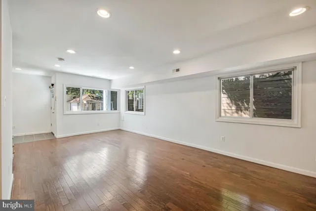 a view of an empty room with a window and wooden floor