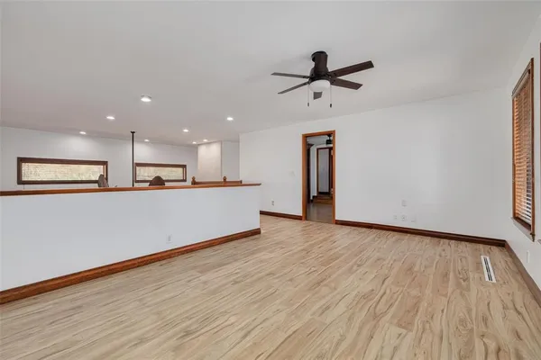 a view of an empty room with wooden floor and a window