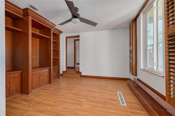 a view of an empty room with window and wooden floor