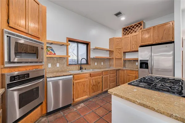 a kitchen with stainless steel appliances granite countertop a stove a sink and a refrigerator