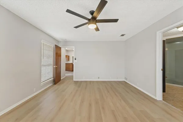 a view of empty room with wooden floor and ceiling fan