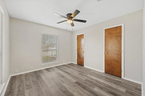 a view of empty room with wooden floor and fan