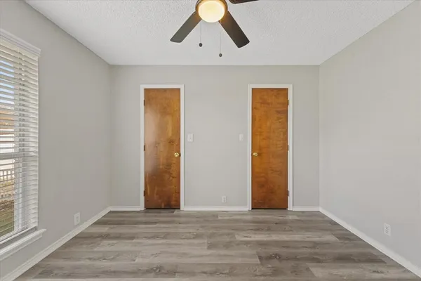 a view of an empty room with wooden floor and window
