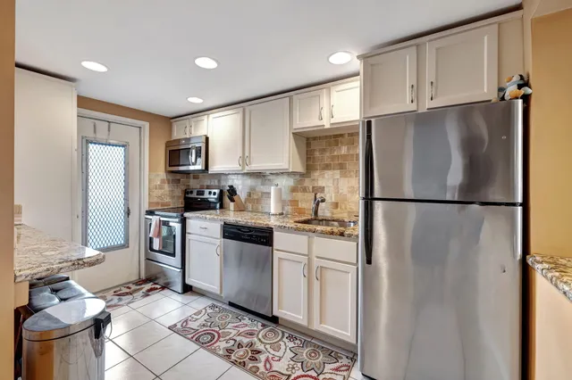 a kitchen with stainless steel appliances granite countertop a refrigerator sink and stove