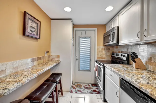 a kitchen with granite countertop kitchen island stainless steel appliances a stove refrigerator sink and cabinets