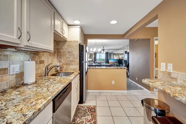 a kitchen with granite countertop a sink a stove and cabinets