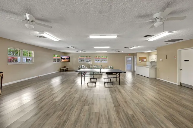 a view of a big room with wooden floor a ceiling fan and windows