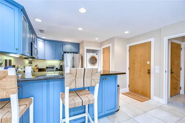 a kitchen with stainless steel appliances granite countertop a refrigerator a sink dishwasher and wooden cabinets with wooden floor