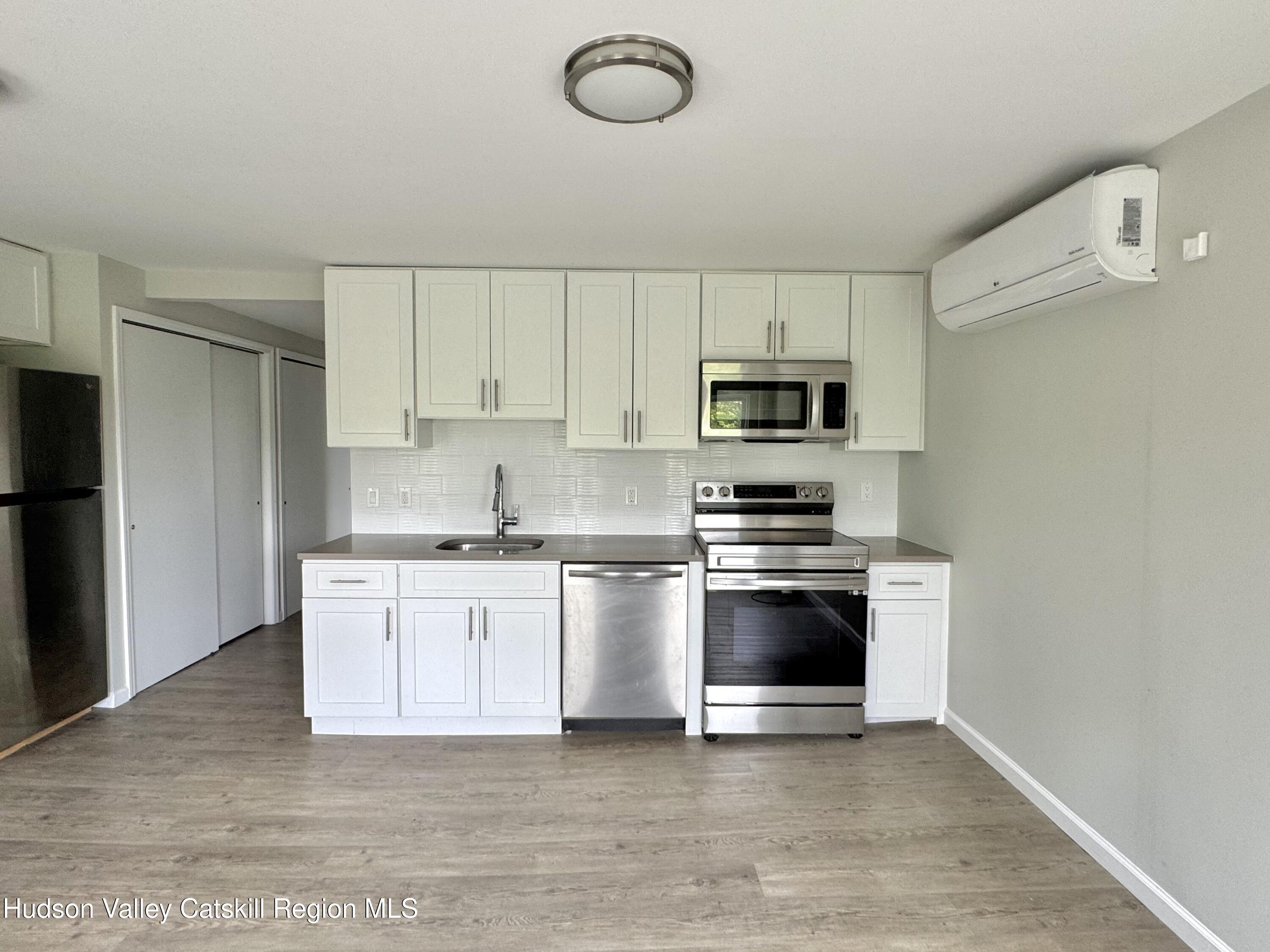 218 Water Street, Unit 5 Catskill, NY 12414 - Photo 3 of 12 a kitchen with granite countertop a stove top oven a sink and a microwave