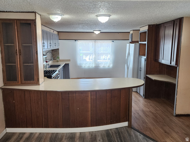 332 Joshua Street Tooele, UT 84074 - Photo 13 of 16 Open-concept kitchen with a breakfast bar featuring wood paneling, wood-finish flooring, built-in cabinetry, and a ceiling light fixture