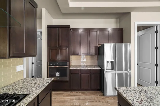 a kitchen with kitchen island granite countertop wooden cabinets and refrigerator